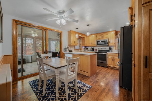 a kitchen with stainless steel appliances a dining table chairs stove refrigerator and cabinets