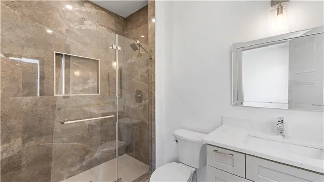 a bathroom with a granite countertop sink a toilet and shower