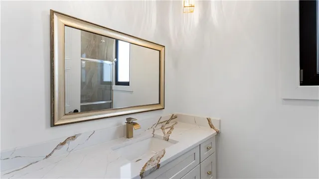 a bathroom with a granite countertop sink and a mirror