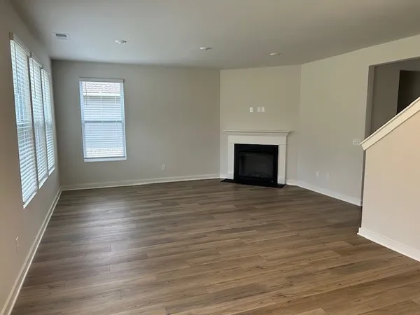 an empty room with wooden floor cabinet and windows