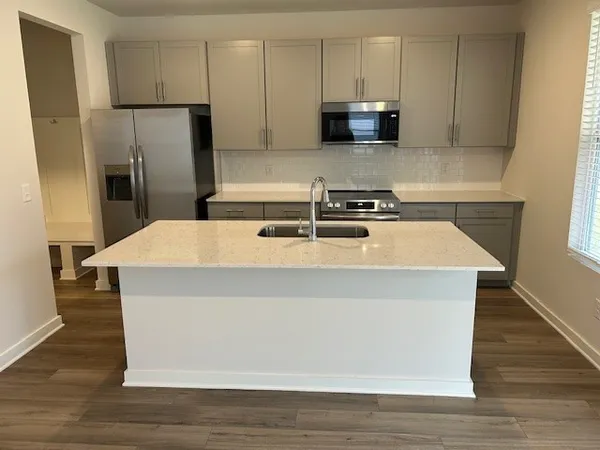 a kitchen with stainless steel appliances a refrigerator a stove a sink and white cabinets