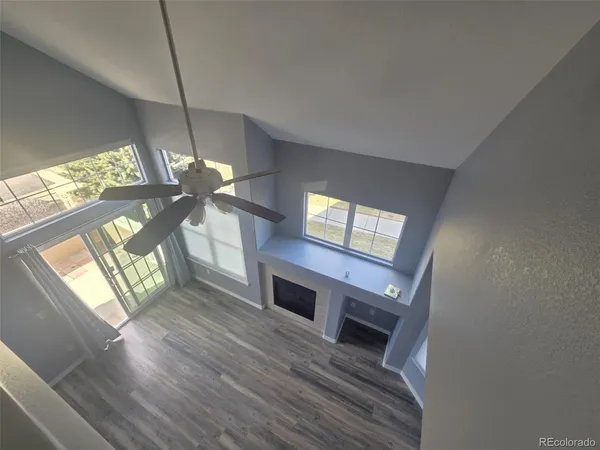 a view of an empty room with wooden floor fireplace and a window