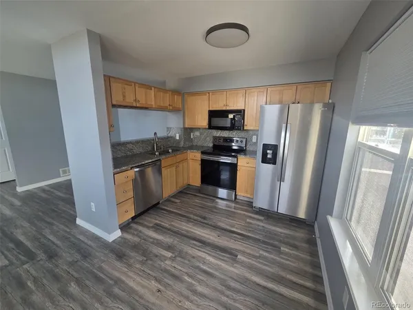 a kitchen with stainless steel appliances granite countertop a refrigerator a stove top oven a sink and dishwasher