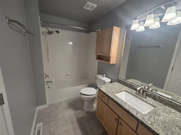 a bathroom with a granite countertop sink toilet and shower