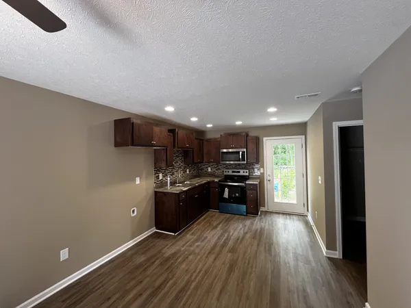 a view of kitchen with refrigerator stove and wooden floor