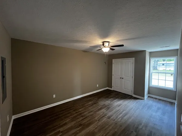 a view of an empty room with wooden floor and a window