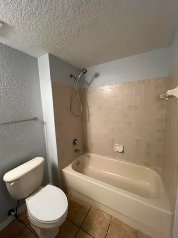 a white toilet sitting next to a bath tub and a shower