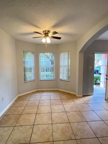 a view of an empty room with windows and chandelier fan