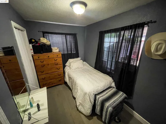 a bedroom with a bed a flat tv screen and dresser