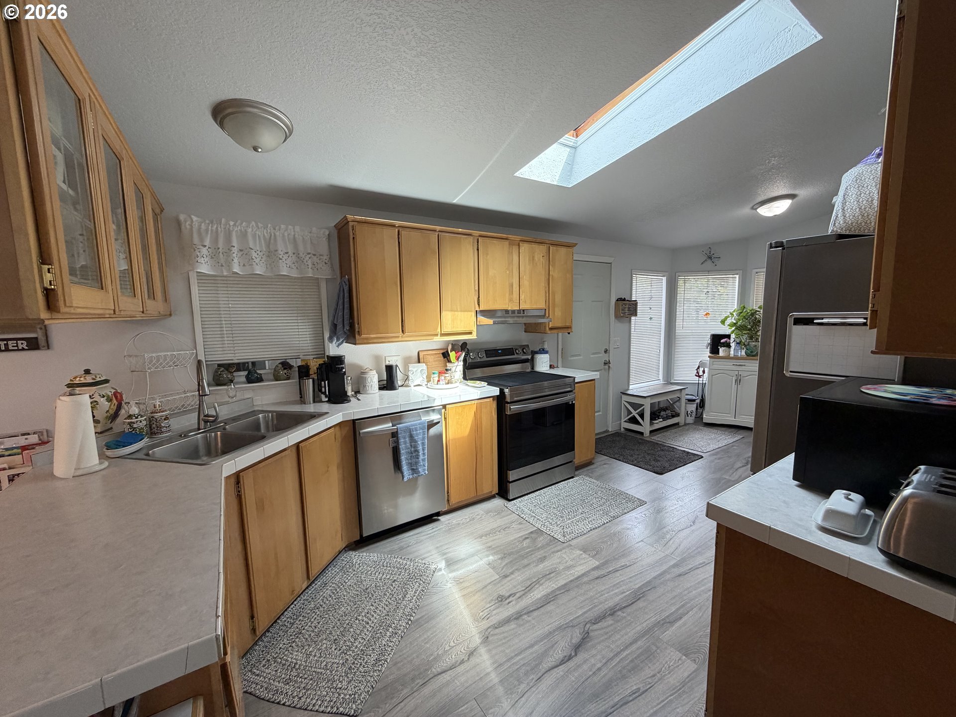 1699 North Terry Street, Unit 351 Eugene, OR 97402 - Photo 9 of 23 a kitchen with stainless steel appliances granite countertop wooden cabinets a sink dishwasher a stove and a refrigerator with wooden floor