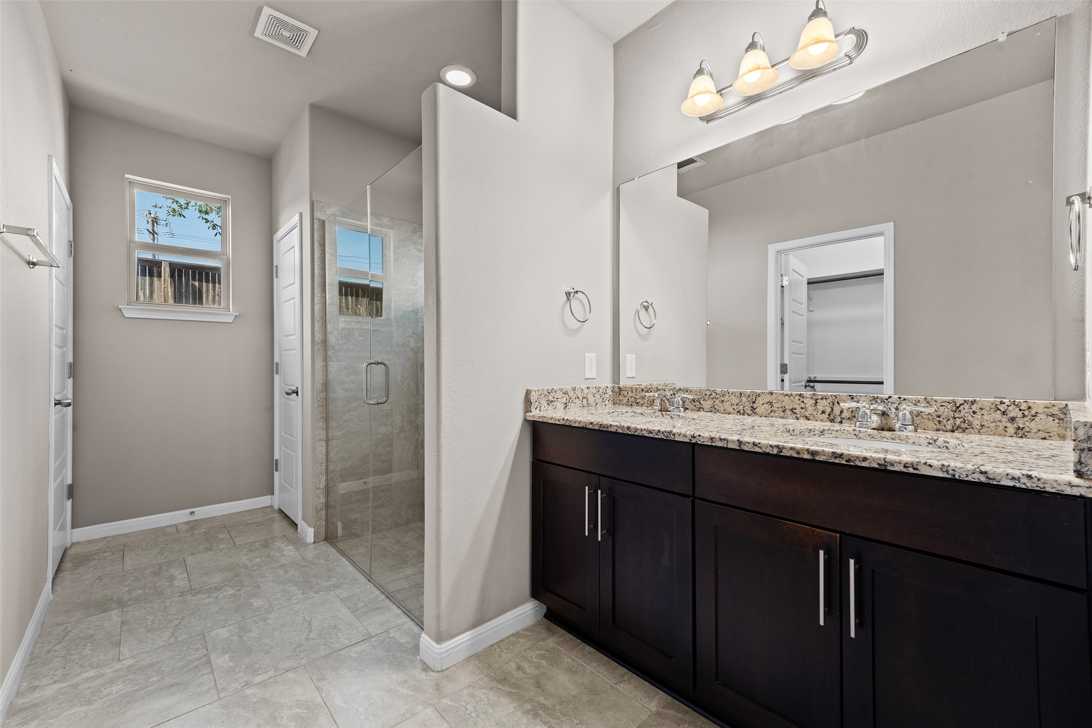 7233 Menchaca Road, Unit 2 Austin, TX 78745 - Photo 25 of 34 a bathroom with a granite countertop sink a large mirror and a shower