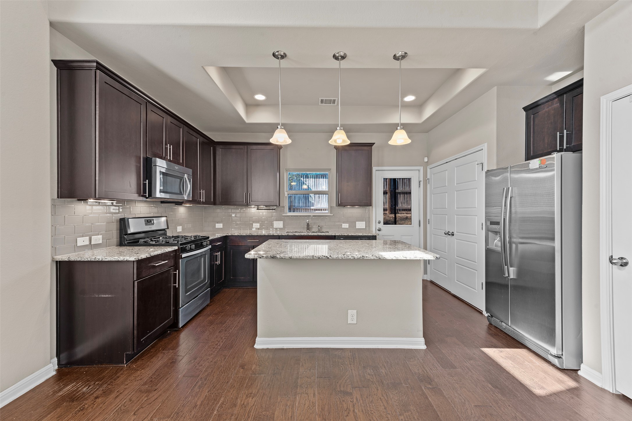 7233 Menchaca Road, Unit 2 Austin, TX 78745 - Photo 6 of 34 a kitchen with stainless steel appliances granite countertop a stove top oven a refrigerator a sink and dishwasher with wooden floor