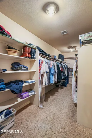a view of walk in closet with clothes and shoes