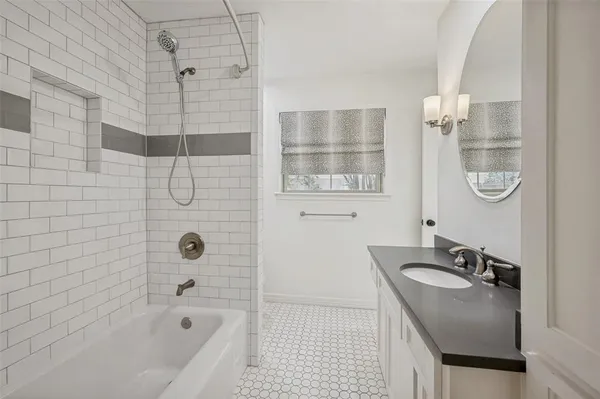a bathroom with a granite countertop sink a mirror and a bathtub