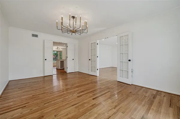 a view of empty room with wooden floor and kitchen view
