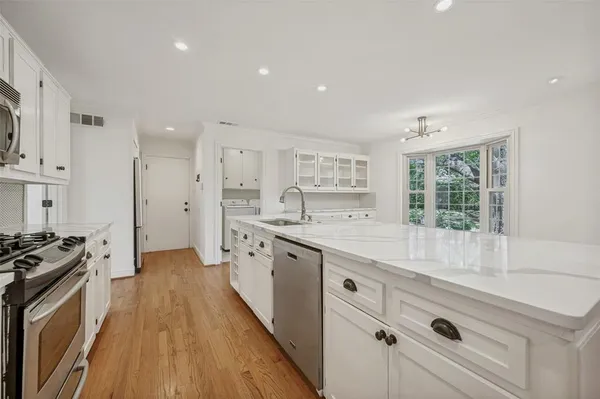 a large kitchen with stainless steel appliances a large counter top a stove a chimney a sink and a refrigerator