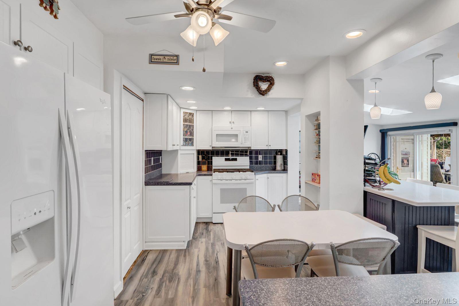 451 North Grove Street Valley Stream, NY 11580 - Photo 18 of 38 a kitchen with stainless steel appliances a white refrigerator a sink dishwasher a dining table and chairs with wooden floor