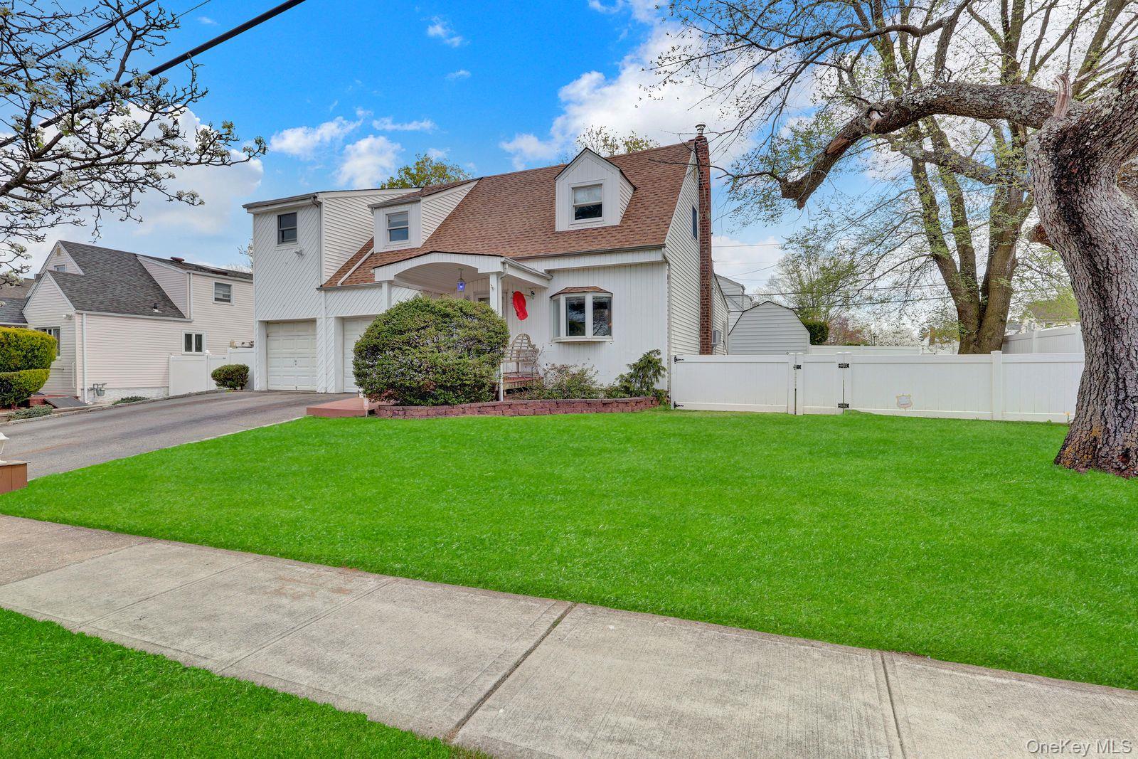 451 North Grove Street Valley Stream, NY 11580 - Photo 2 of 38 a front view of a house with a garden and yard