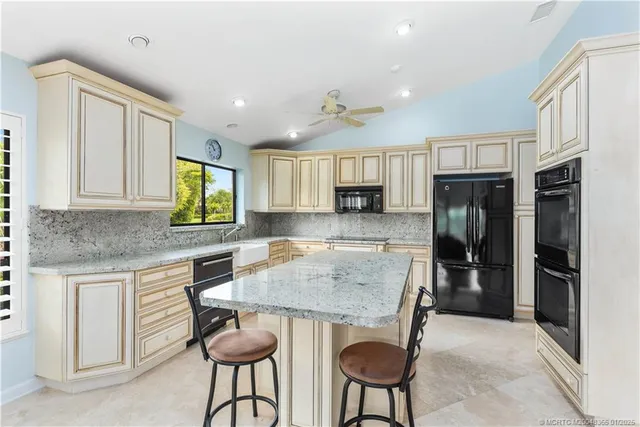 a kitchen with stainless steel appliances granite countertop a stove top oven a refrigerator a sink and a cabinets