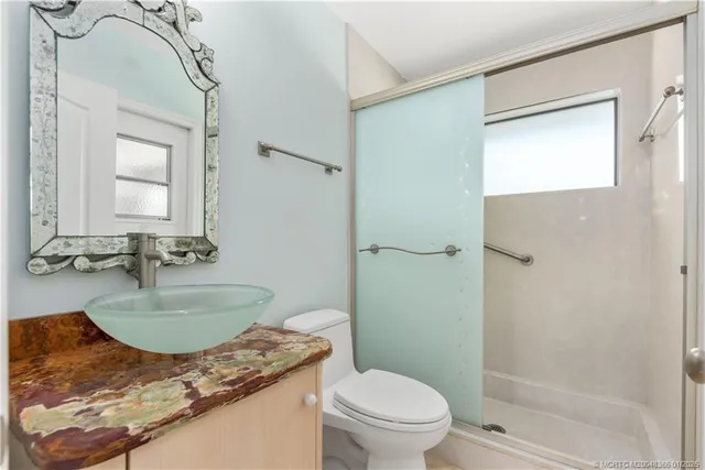 a bathroom with a granite countertop sink a mirror and a toilet
