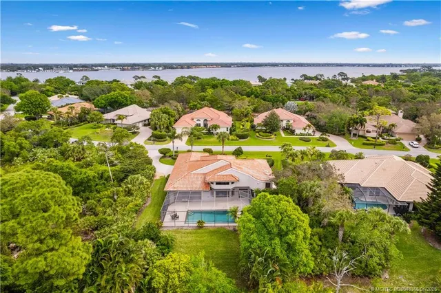 an aerial view of residential houses with outdoor space and trees all around