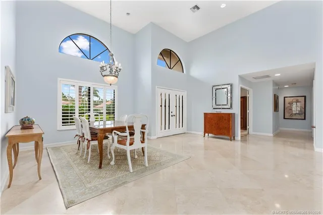 a dining room with furniture and a chandelier fan