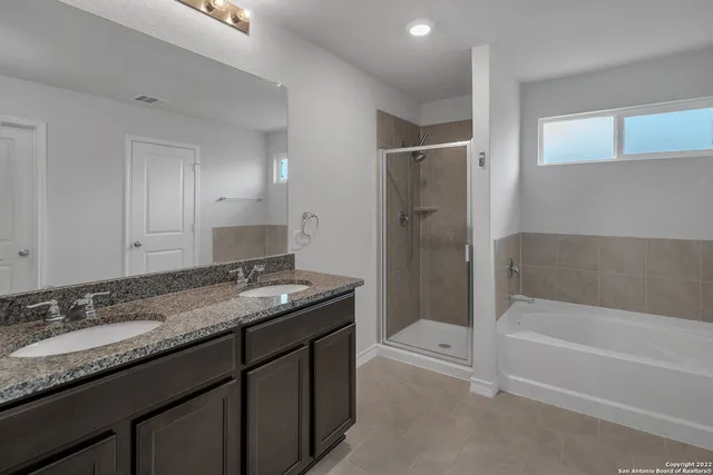 a bathroom with a granite countertop sink a mirror a bathtub and shower