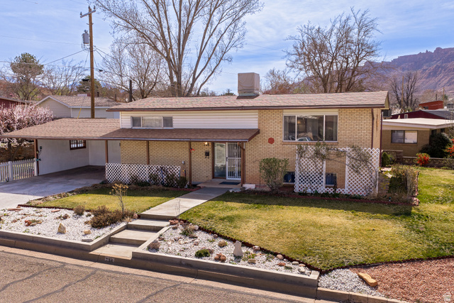 738 Locust Lane Moab, UT 84532 - Photo 1 of 25 View of front of home with a chimney, an attached carport, brick siding, and driveway
