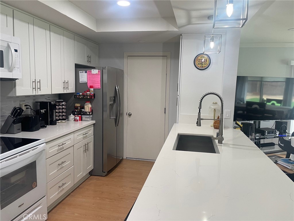 26592 Farrell Street Menifee, CA 92586 - Photo 7 of 31 a kitchen with granite countertop a stove a sink and a refrigerator