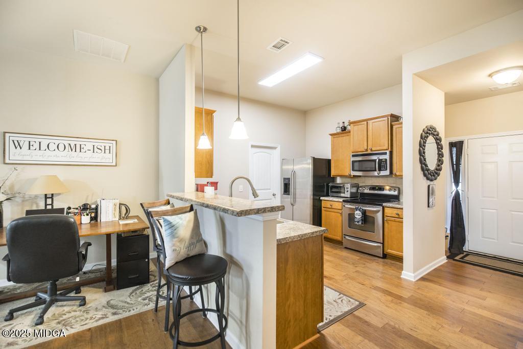 135 Abelia Lane Byron, GA 31008 - Photo 12 of 32 a kitchen with stainless steel appliances kitchen island granite countertop a refrigerator a stove top oven a sink dishwasher and chairs with wooden floor