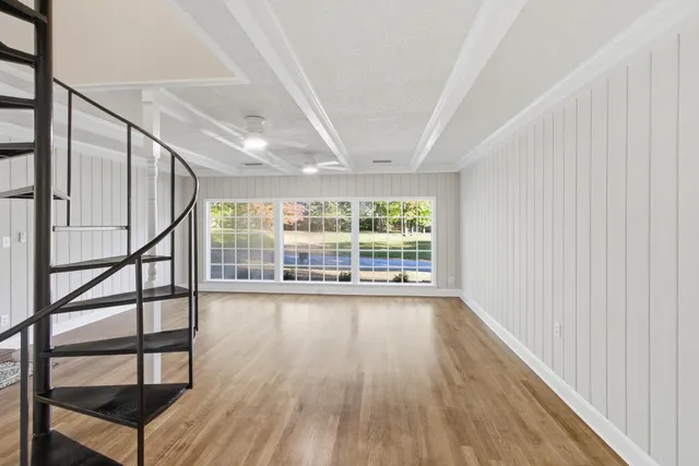 a view of empty room with wooden floor and ceiling fan