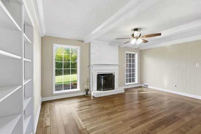 a view of an empty room with wooden floor and a fireplace