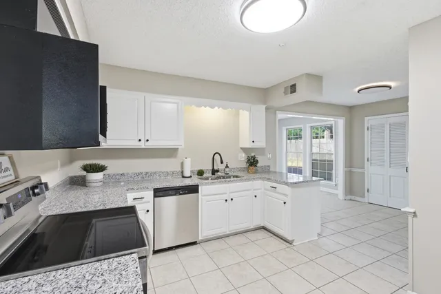 a kitchen with granite countertop a sink a stove top oven and cabinets