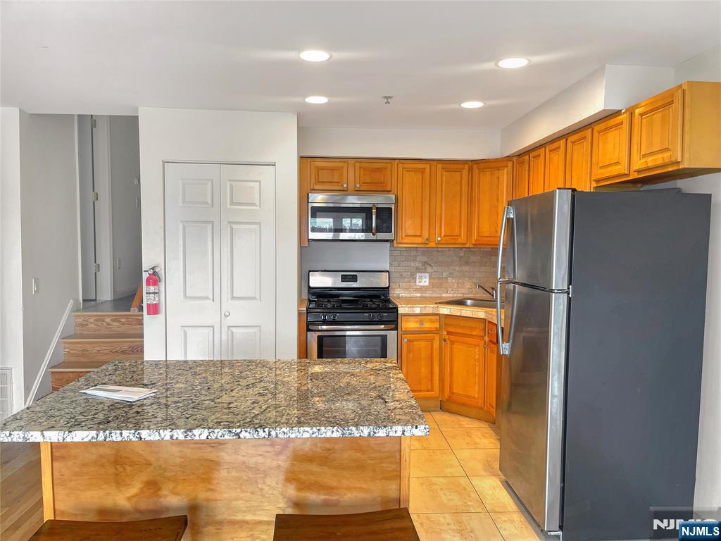 8913 Riverside Place, Unit 3 North Bergen, NJ 07047 - Photo 5 of 17 a kitchen with granite countertop a refrigerator and a sink