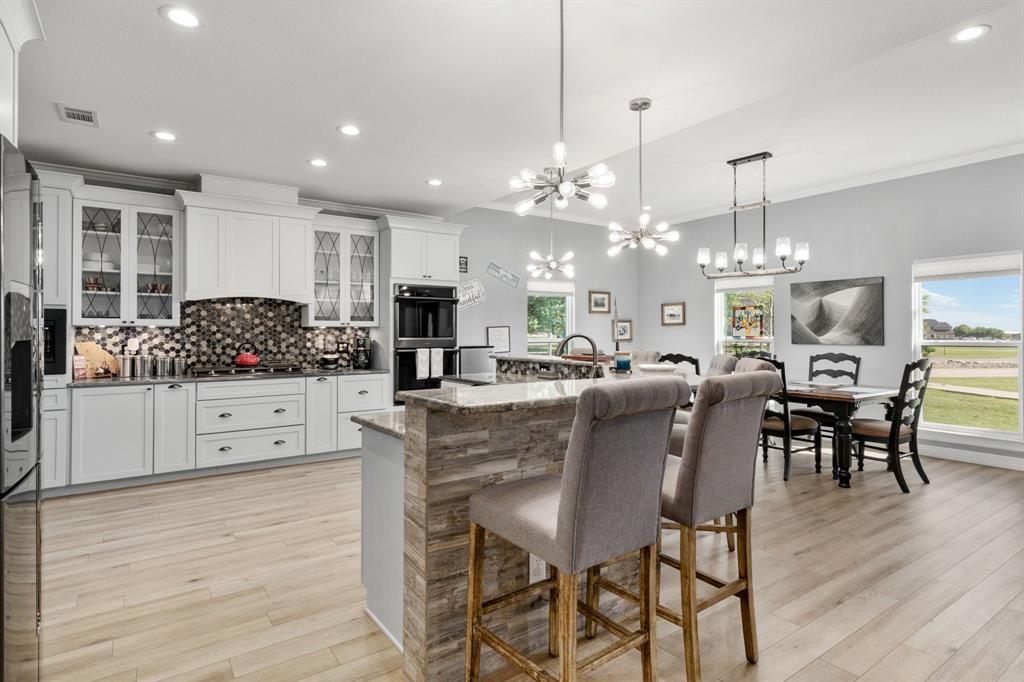10832 Ridge Country Road Haslet, TX 76052 - Photo 6 of 30 a kitchen with stainless steel appliances kitchen island granite countertop a table and chairs in it