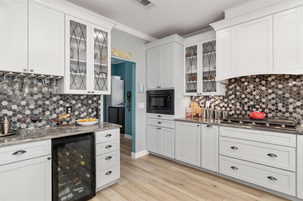 10832 Ridge Country Road Haslet, TX 76052 - Photo 10 of 30 Wine fridge below the wine bar, microwave surrounded by tons of storage, & pull-out spice drawers & utensil caddy on each side of the cooktop.