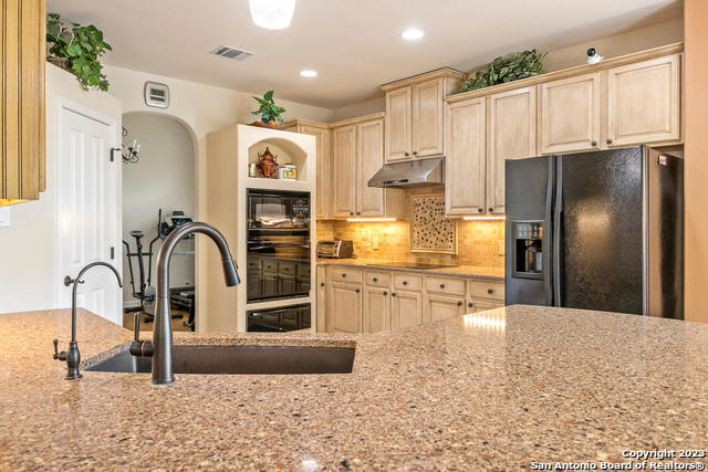 9634 Jason Bend Helotes, TX 78023 - Photo 14 of 43 a kitchen with stainless steel appliances kitchen island granite countertop a refrigerator and a sink