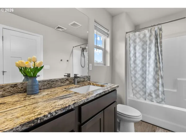 a bathroom with a granite countertop sink a toilet and a mirror
