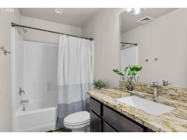 a bathroom with a granite countertop sink a toilet and shower
