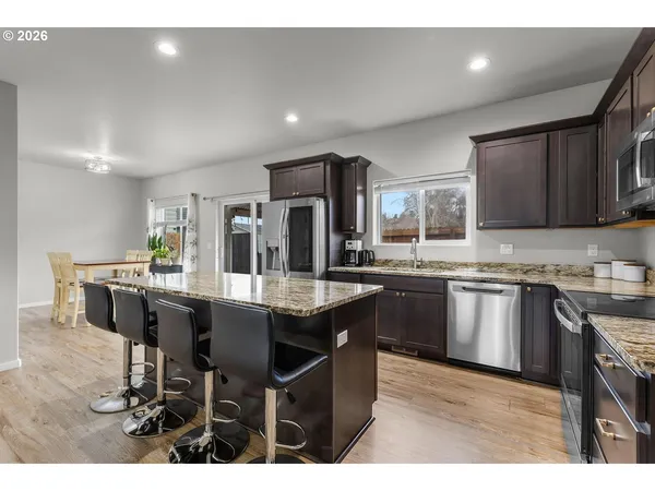 a kitchen with stainless steel appliances granite countertop table chairs sink and cabinets