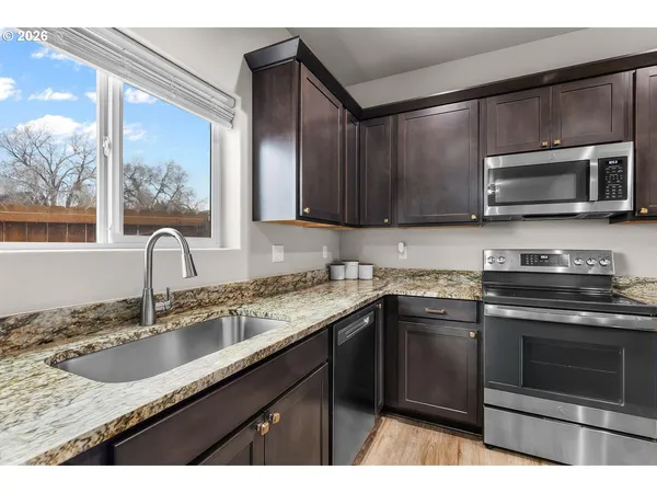 a kitchen with granite countertop a sink stove and microwave