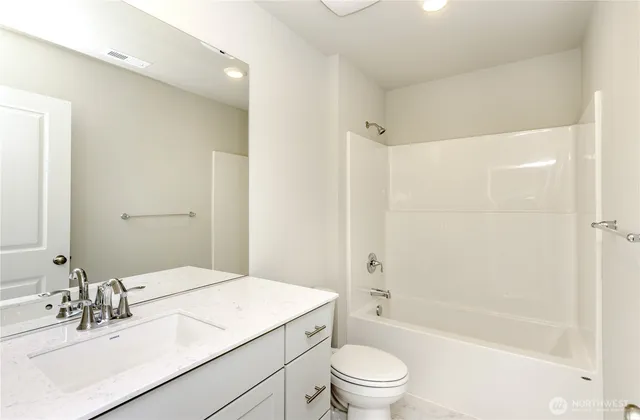 a bathroom with a granite countertop sink a toilet a mirror and shower
