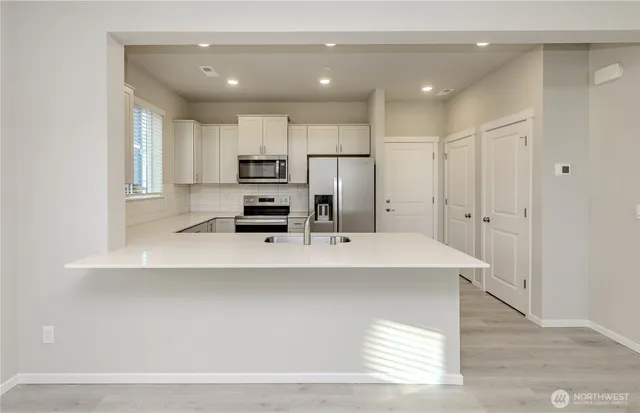 a large white kitchen with kitchen island a stove a sink and a refrigerator
