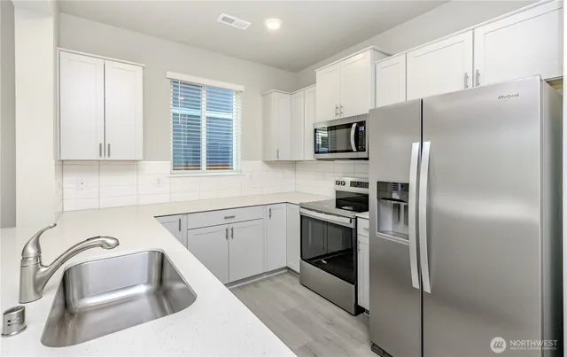 a kitchen with stainless steel appliances granite countertop a refrigerator sink and stove