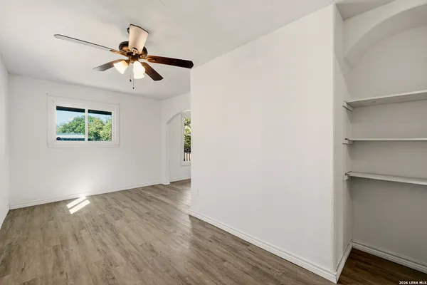 a view of an empty room with wooden floor and a window