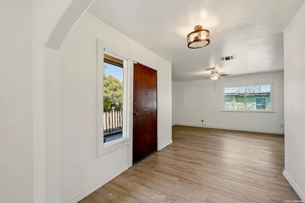 an empty room with wooden floor cabinet and windows