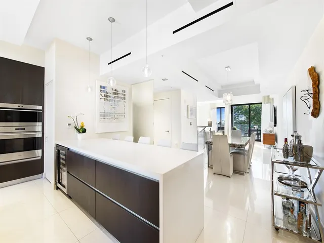 a large white kitchen with a large window appliances and cabinets