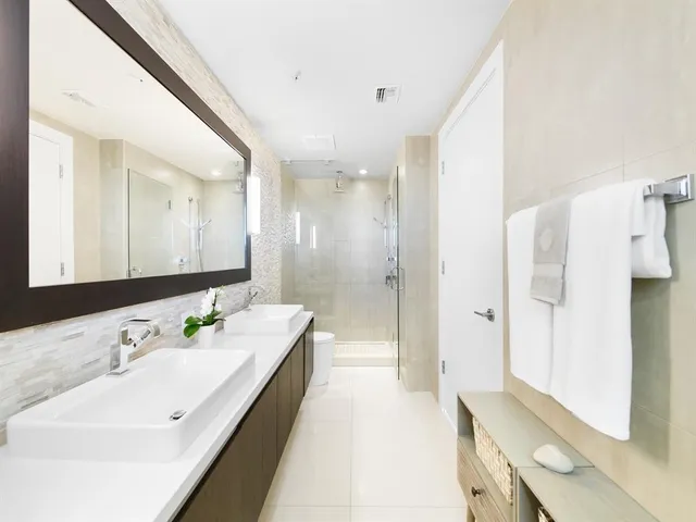 a en suite bathroom with a double vanity sink a mirror and a shower