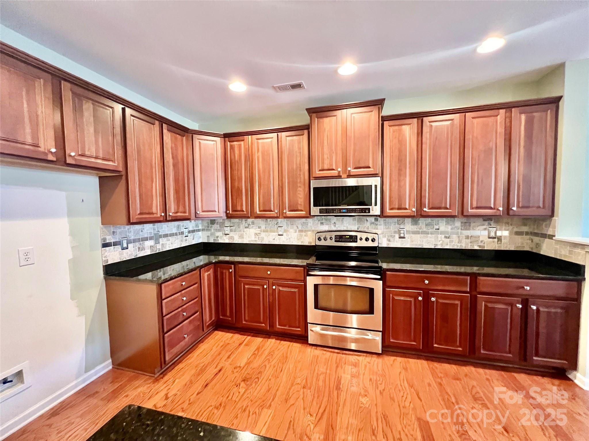 8326 Viewpoint Lane, Unit 802 Cornelius, NC 28031 - Photo 12 of 43 a kitchen with stainless steel appliances granite countertop wooden cabinets a sink and dishwasher with wooden floor