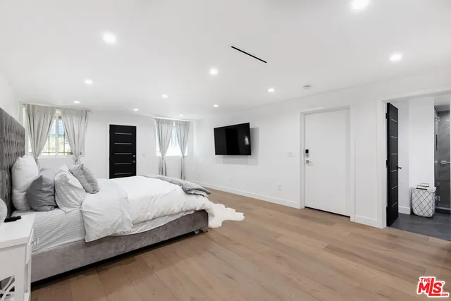 a spacious bedroom with a bed and a flat screen tv